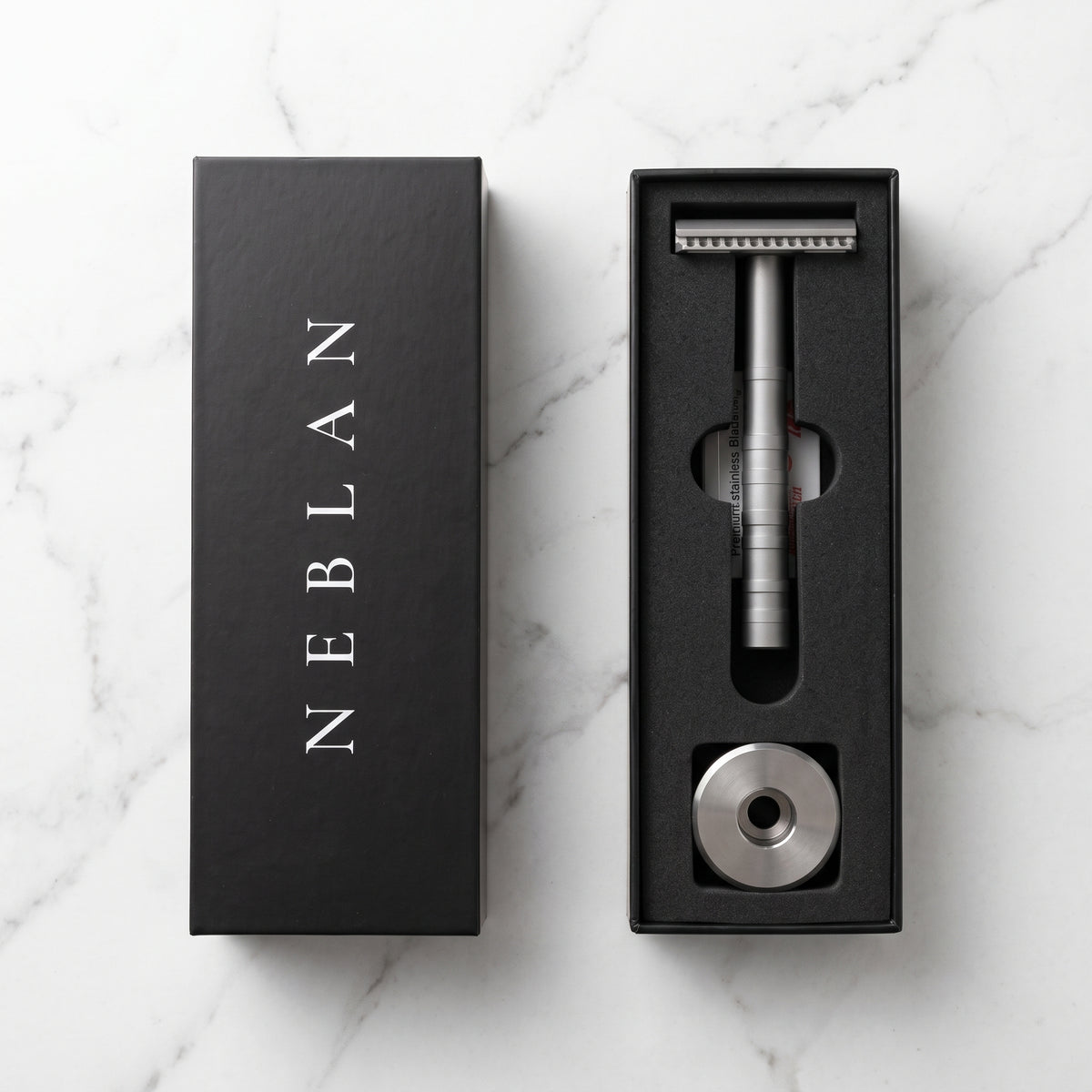 Coffret Neblan ouvert : rasoir de sûreté, support en acier et étui de 10 lames dans la mousse noire