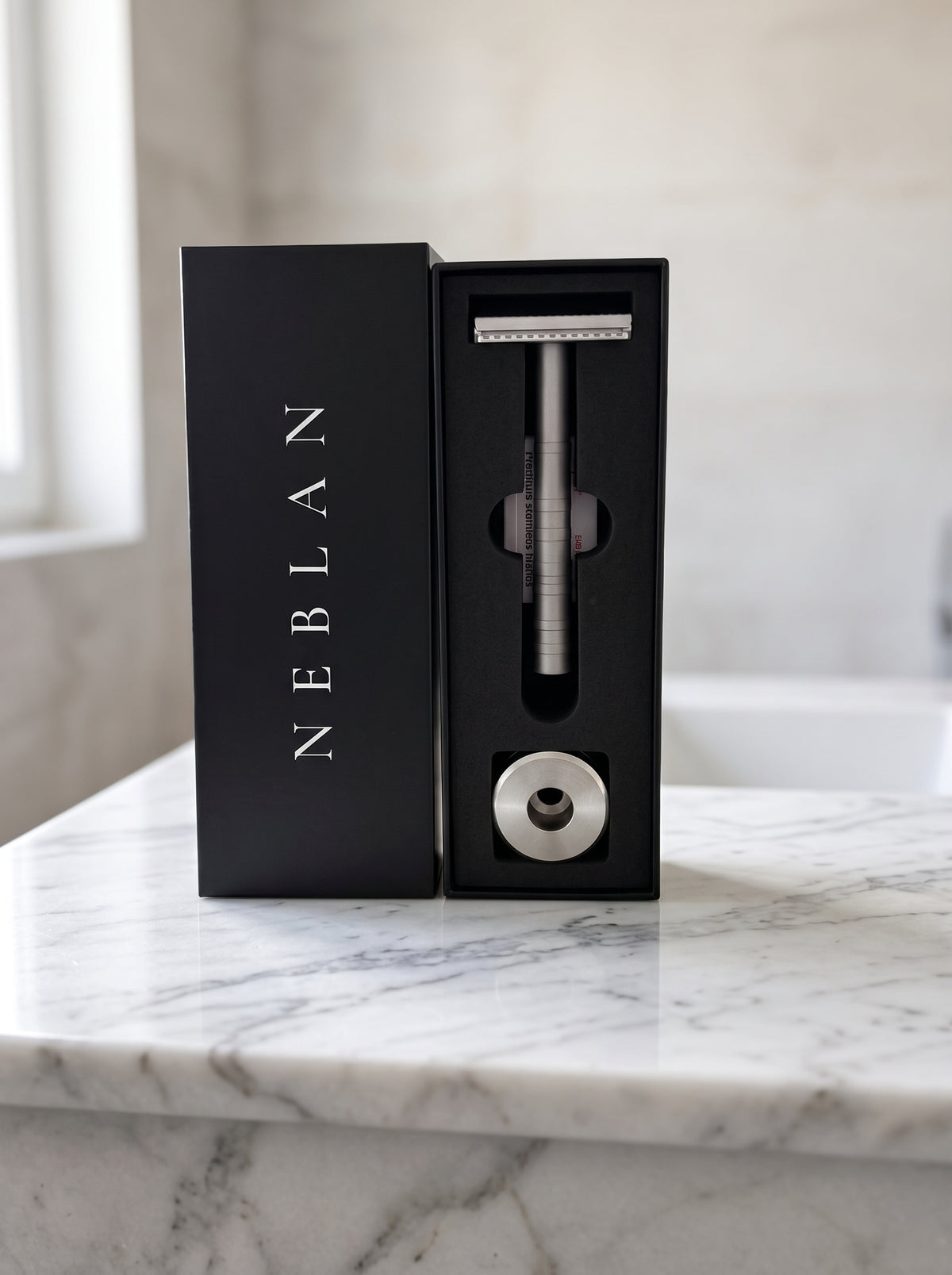 Coffret Neblan debout sur un plan de vasque en marbre, avec le rasoir et son support